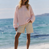 Model wearing the Hailey Mini Striped Pink Button Down Cardigan by the beach