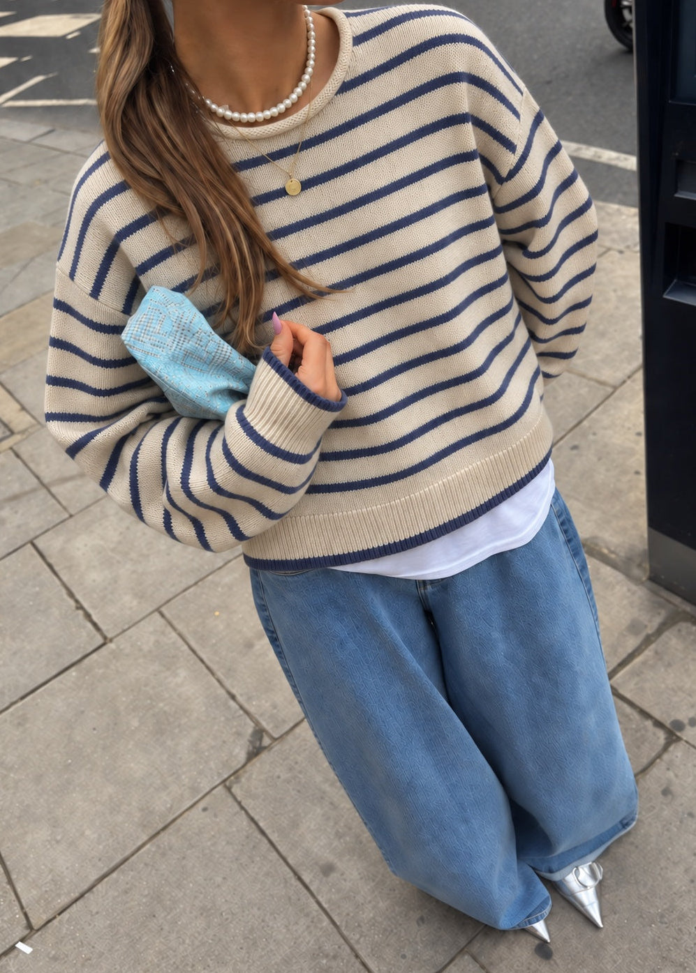 Model wearing the Harbor Striped Rollneck Sweater in light butter cream with blue stripes, dropped shoulders, and blue-tipped cuffs and hem.