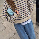 Model wearing the Harbor Striped Rollneck Sweater in light butter cream with blue stripes, dropped shoulders, and blue-tipped cuffs and hem.