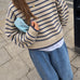 Model wearing the Harbor Striped Rollneck Sweater in light butter cream with blue stripes, dropped shoulders, and blue-tipped cuffs and hem.