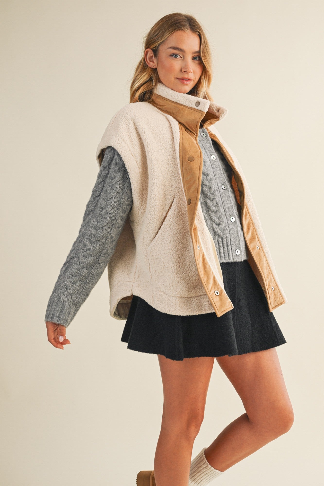 Full-body side view of model wearing the ecru snap vest, showing length and layering fit