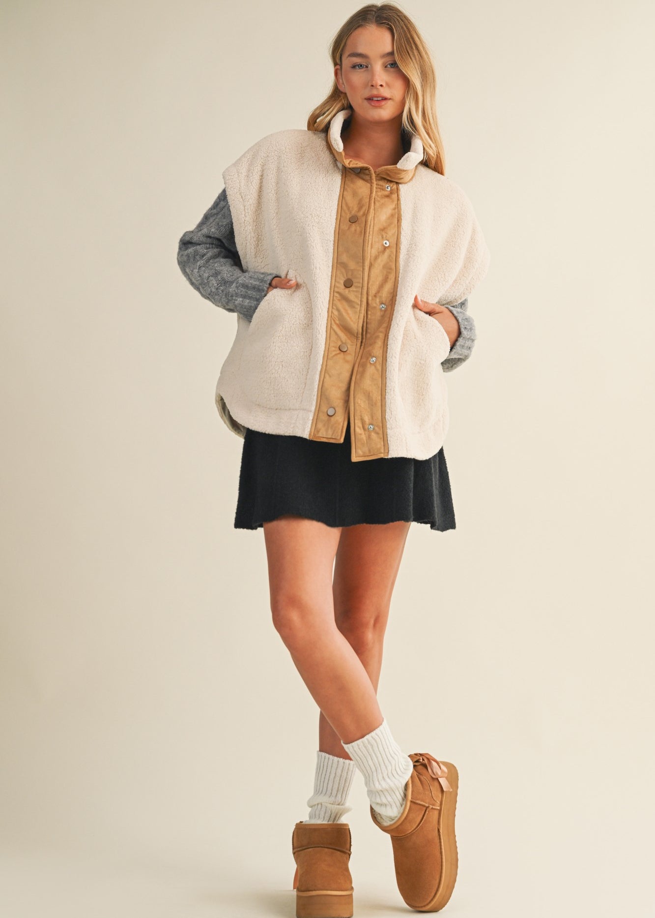 Full-body side view of model wearing the ecru snap vest, showing length and layering fit