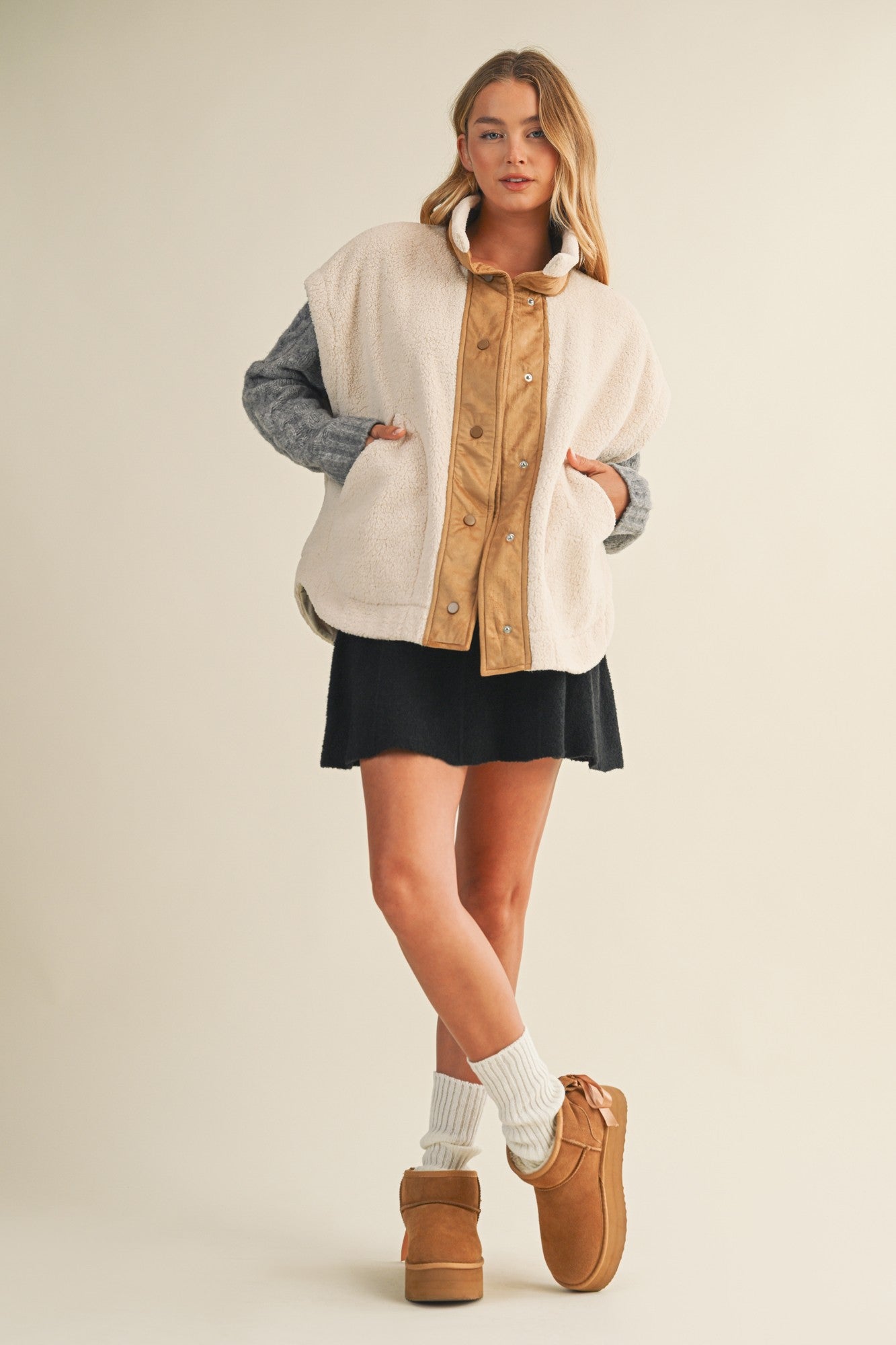 Full-body side view of model wearing the ecru snap vest, showing length and layering fit