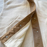 Close-up of the inside placket and snap closure detailing on the ecru vest
