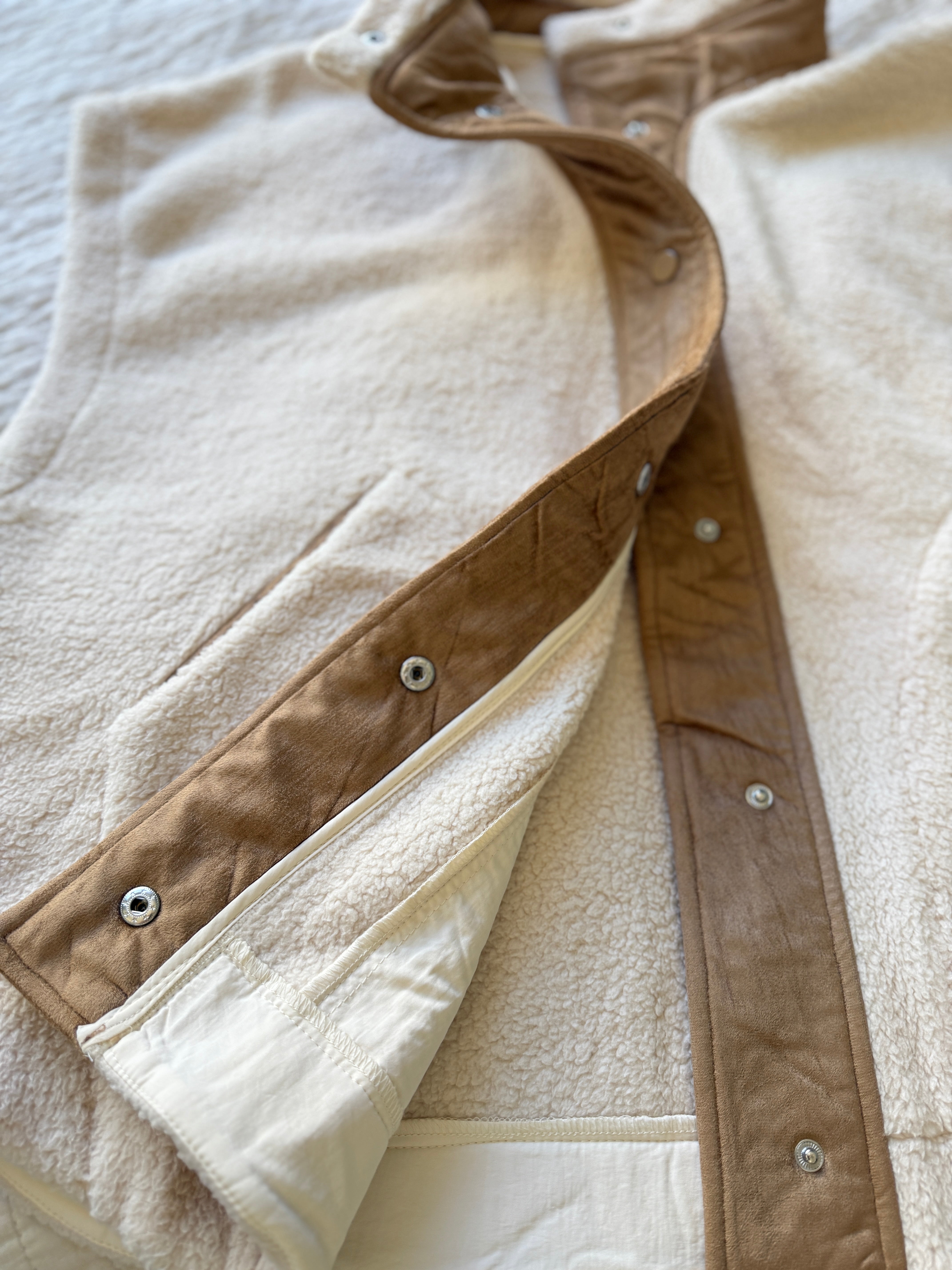 Close-up of the inside placket and snap closure detailing on the ecru vest