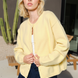 Woman wearing the Harper Round-Neck Relaxed Cardigan in butter yellow with a skirt — stylish, cozy women’s knit cardigan.