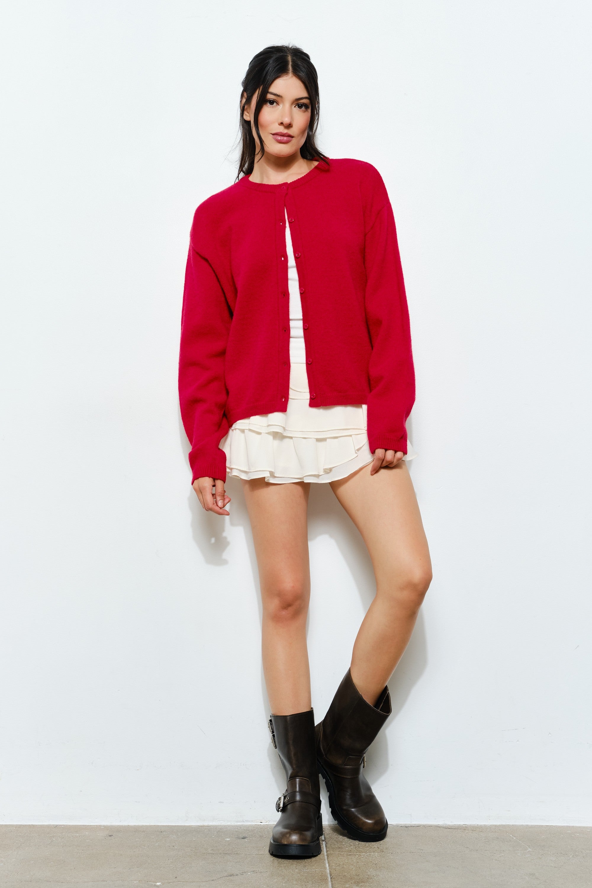 Woman wearing the Harper Round-Neck Relaxed Cardigan in red while seated — cozy and stylish women’s outfit.