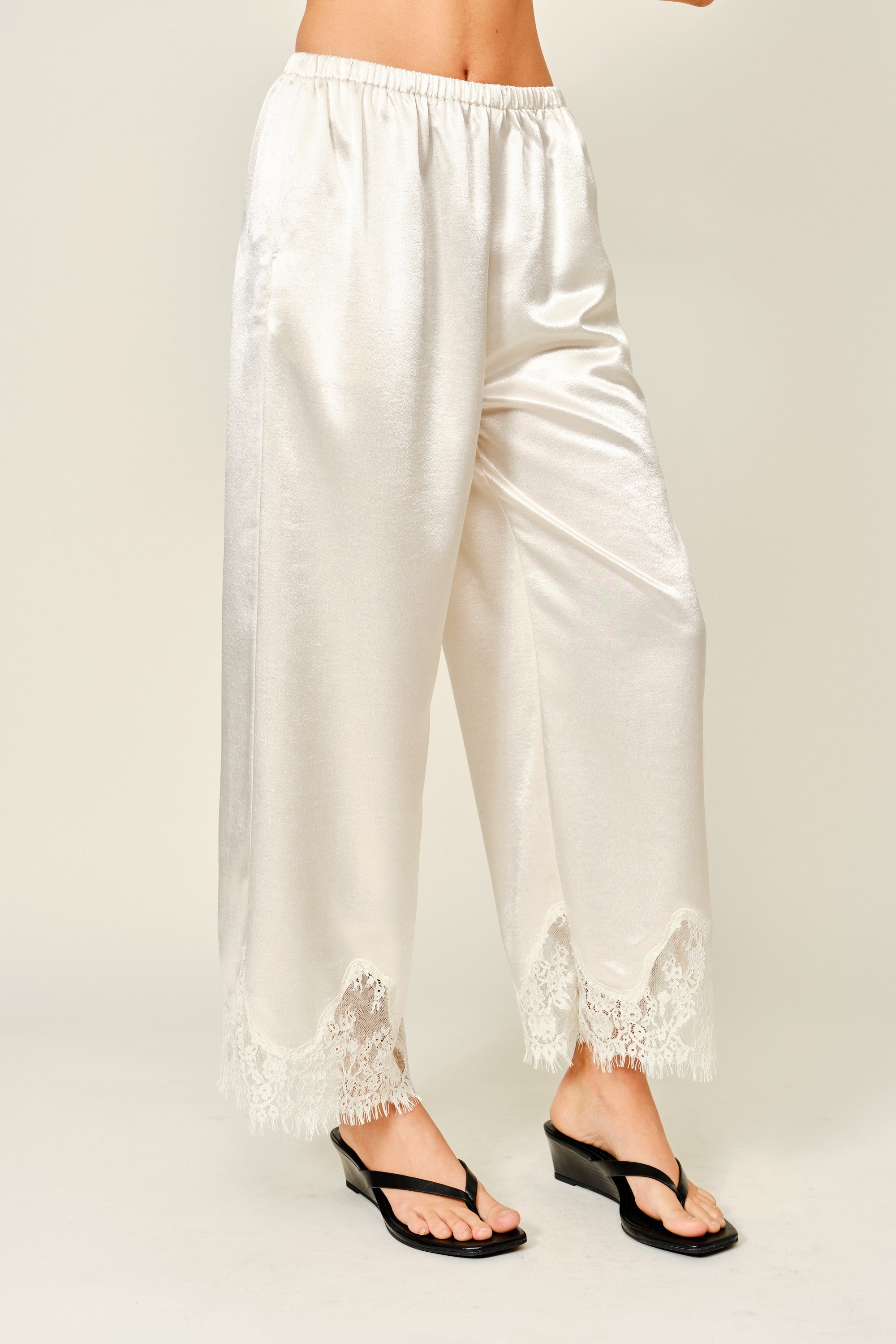 Side view of champagne satin wide-leg pants with soft drape and lace trim hem