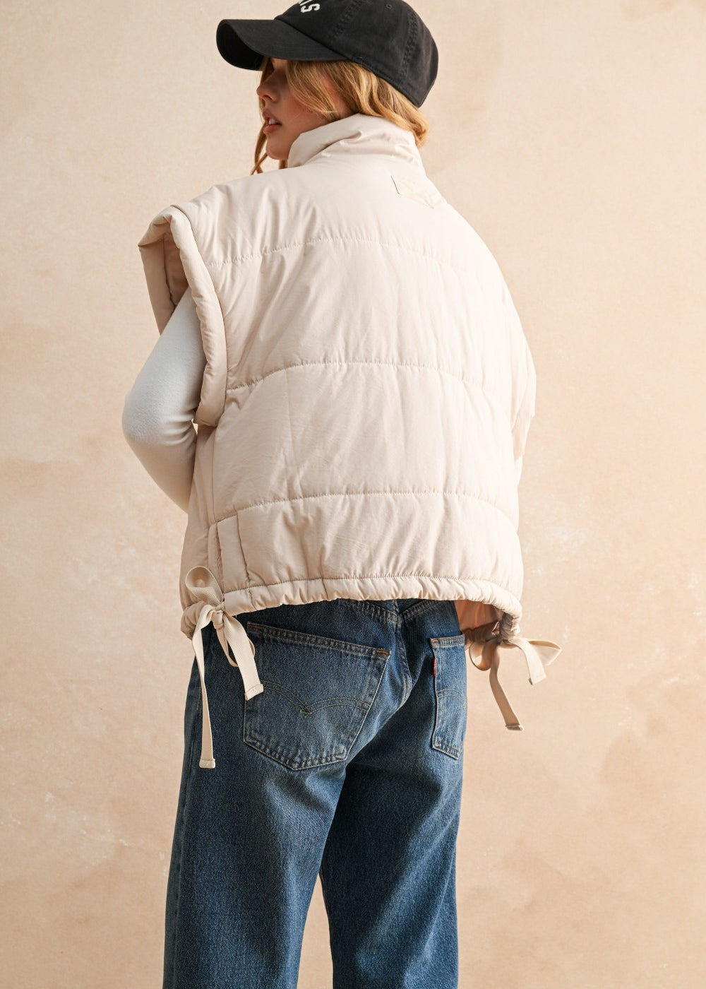 Woman wearing ecru bubble puffer vest in natural outdoor setting — warm and stylish fall outerwear - back view