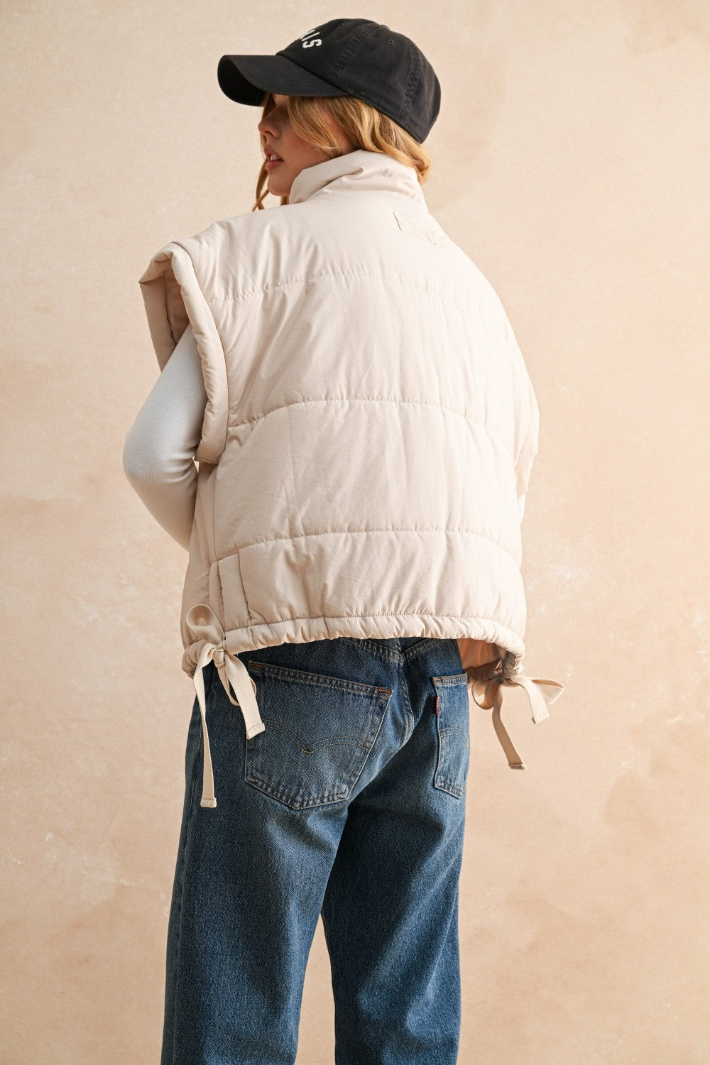 Woman wearing ecru bubble puffer vest in natural outdoor setting — warm and stylish fall outerwear - back view