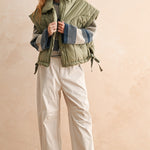 Side view of olive women’s puffer vest showing relaxed fit, adjustable hem, and high neckline — casual fall outfit.