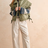 Side view of olive women’s puffer vest showing relaxed fit, adjustable hem, and high neckline — casual fall outfit.