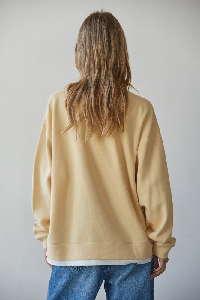Back view of the Jetset butter yellow crewneck sweatshirt with long sleeves and a white layered hem.