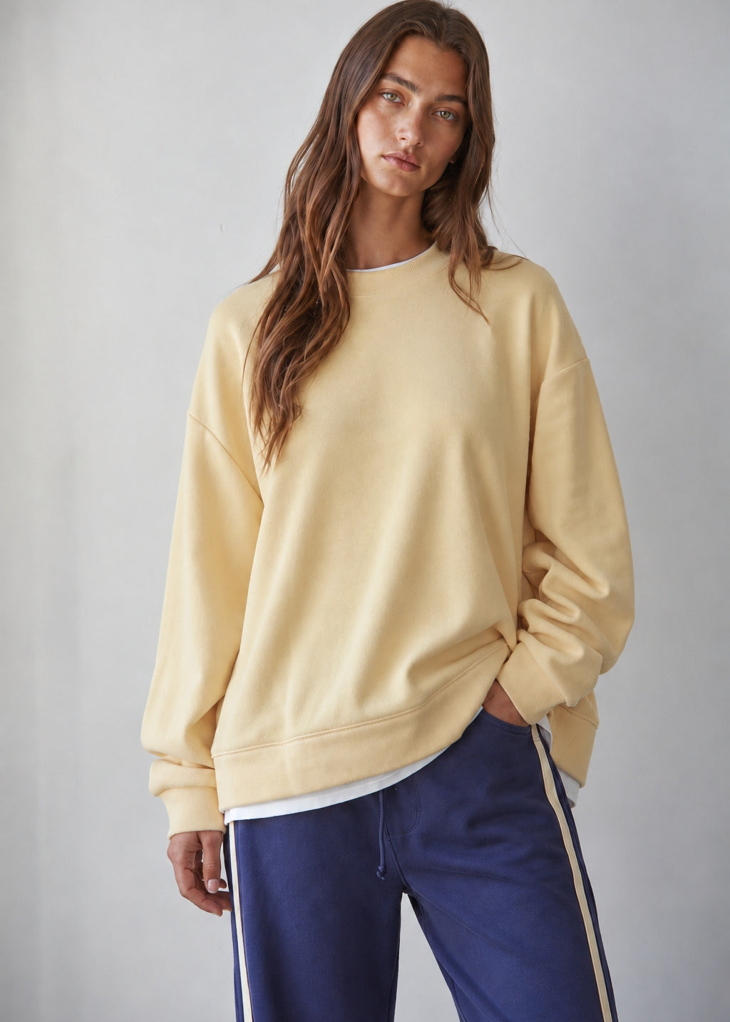 Brunette model wearing the Jetset butter yellow layered sweatshirt with a crew neckline and white contrast hem.