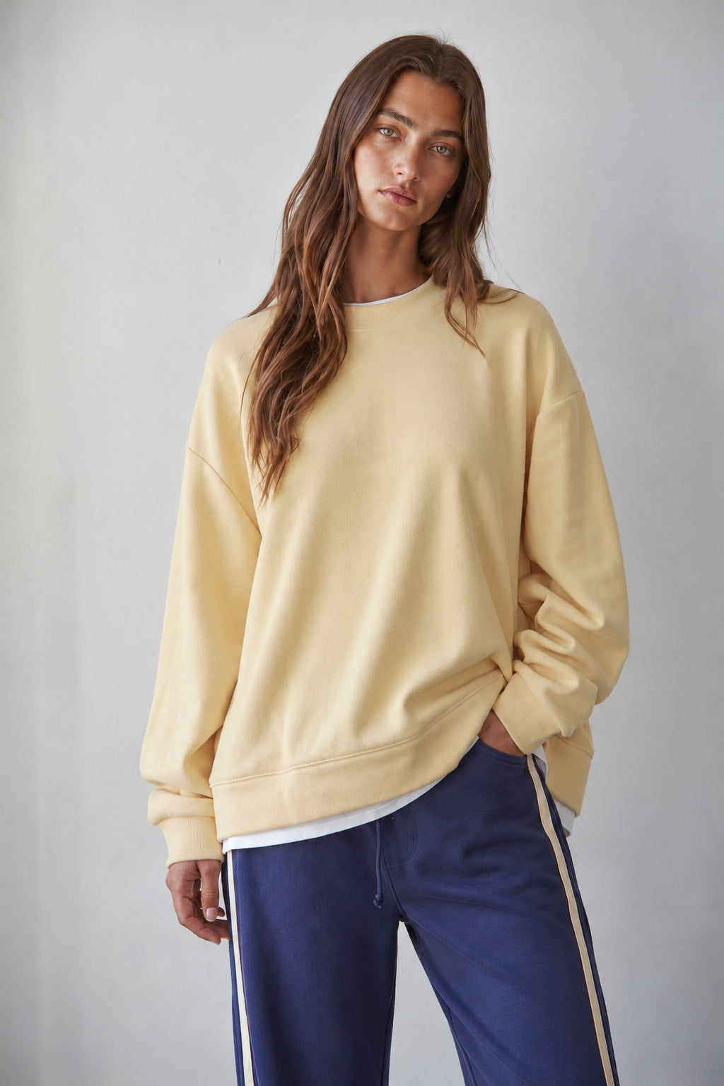 Brunette model wearing the Jetset butter yellow layered sweatshirt with a crew neckline and white contrast hem.
