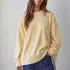 Brunette model wearing the Jetset butter yellow layered sweatshirt with a crew neckline and white contrast hem.