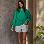 Model wearing the Jetset varsity green layered twofer sweatshirt with cream shorts.