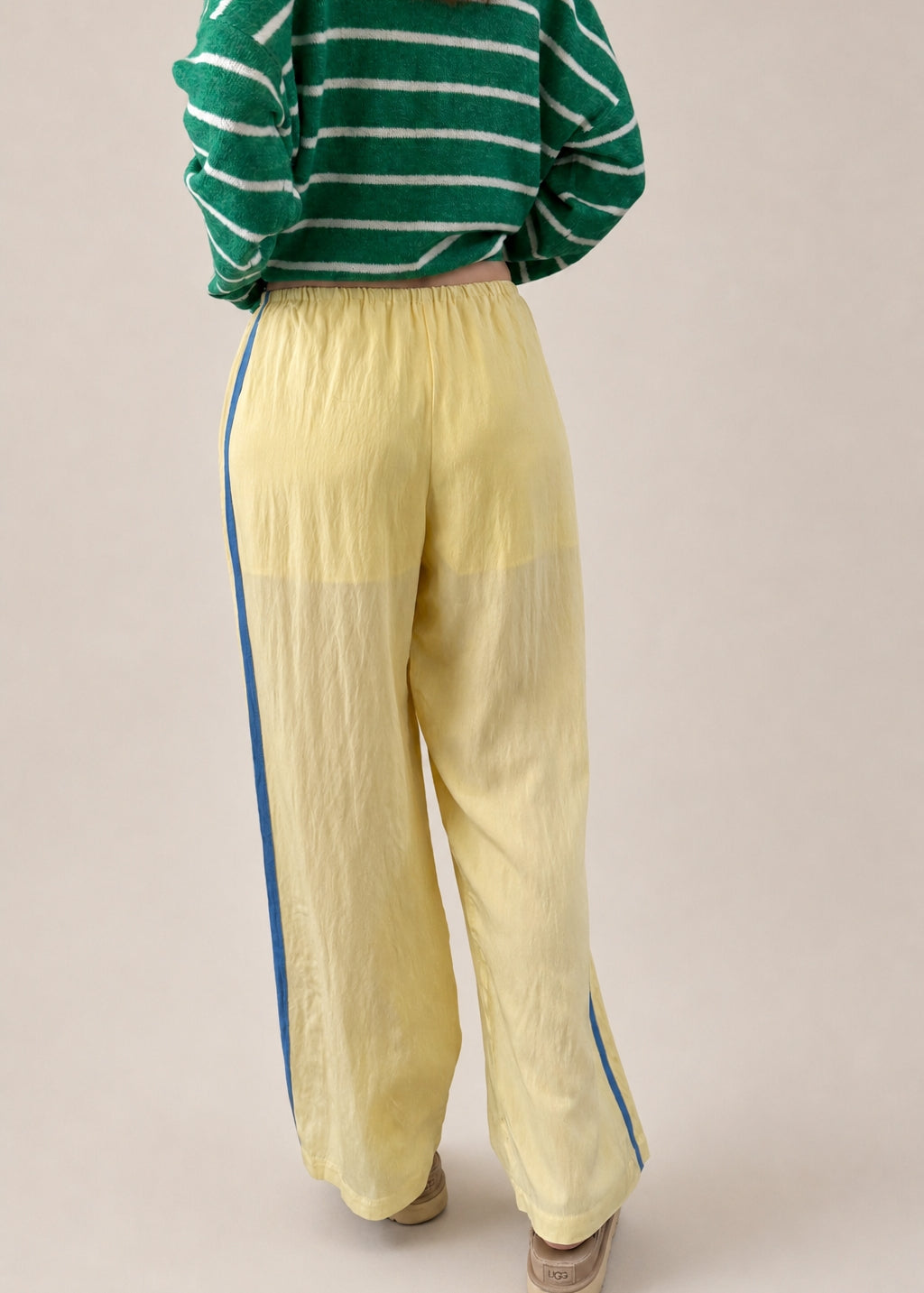 Back view of butter yellow Landon Track Pants showing the blue stripe detail and relaxed pull-on fit.