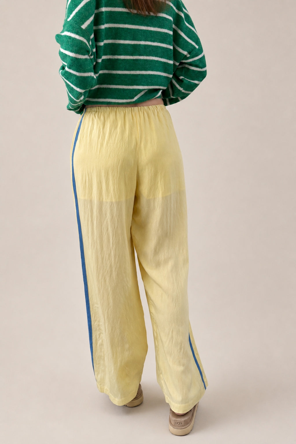 Back view of butter yellow Landon Track Pants showing the blue stripe detail and relaxed pull-on fit.