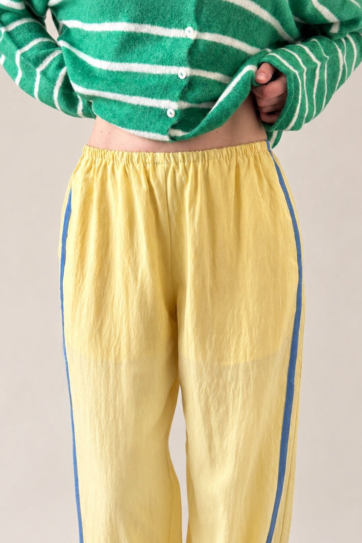 close up photo of  butter yellow Landon Track Pants showing the blue stripe detail and relaxed pull-on fit.