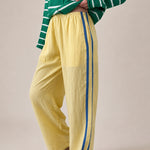 Landon Side Stripe Track Pants in butter yellow with relaxed wide leg fit, elastic waist, and blue side stripe detail - half side view