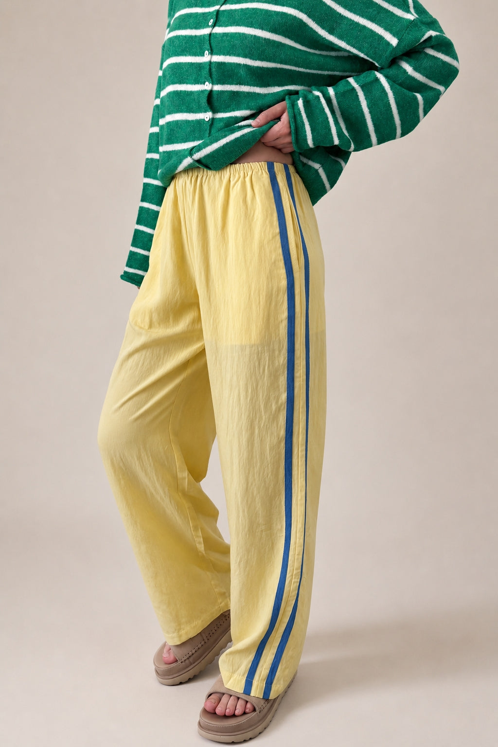 Landon Side Stripe Track Pants in butter yellow with relaxed wide leg fit, elastic waist, and blue side stripe detail - half side view
