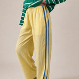 Landon Side Stripe Track Pants in butter yellow with relaxed wide leg fit, elastic waist, and blue side stripe detail - half side view