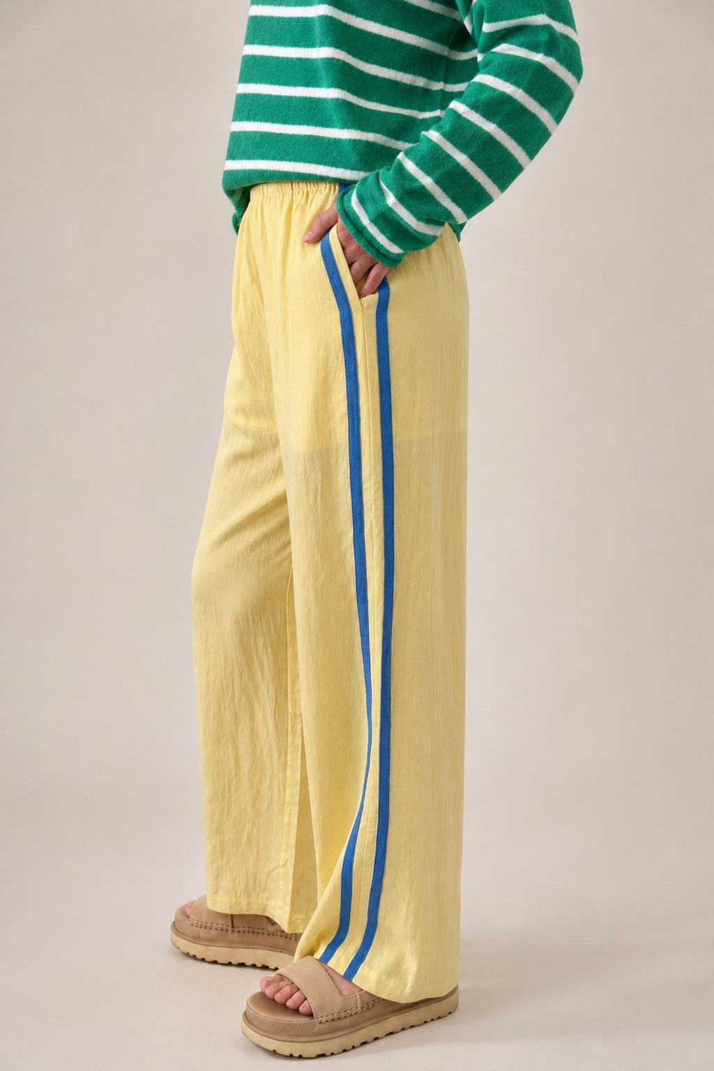 Side view of butter yellow Landon Track Pants showing the blue stripe detail and relaxed pull-on fit.