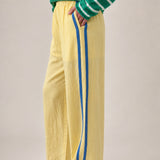 Side view of butter yellow Landon Track Pants showing the blue stripe detail and relaxed pull-on fit.