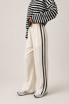 Full length view of the Landon Side Stripe Track Pants in ivory styled for a casual everyday outfit.