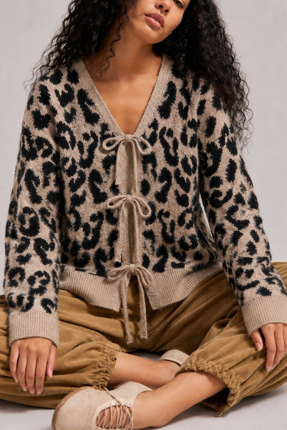 Close-up of the leopard print knit cardigan showing the V-neckline and front bow ties