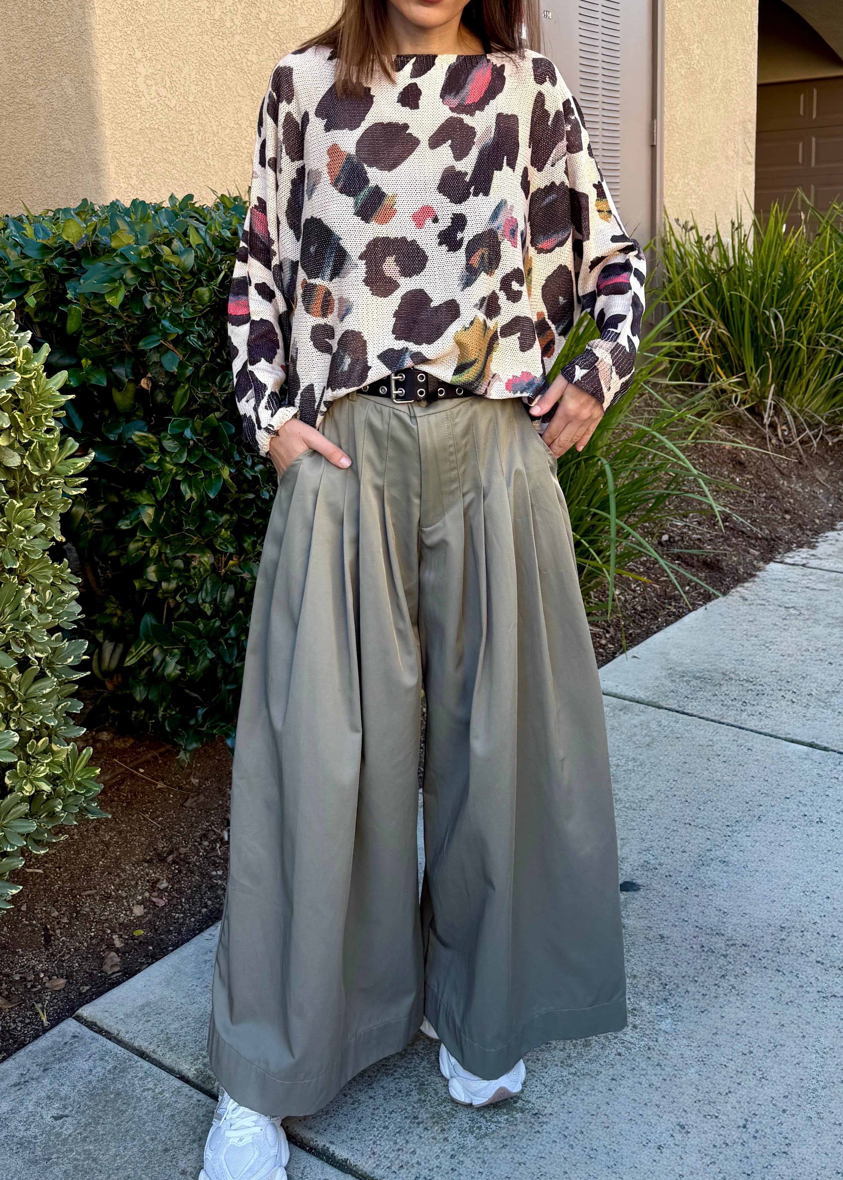 Full-body view of the batwing printed sweater styled with wide-leg pants