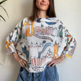 Lifestyle image of model wearing the playful cats print batwing sweater in a casual setting
