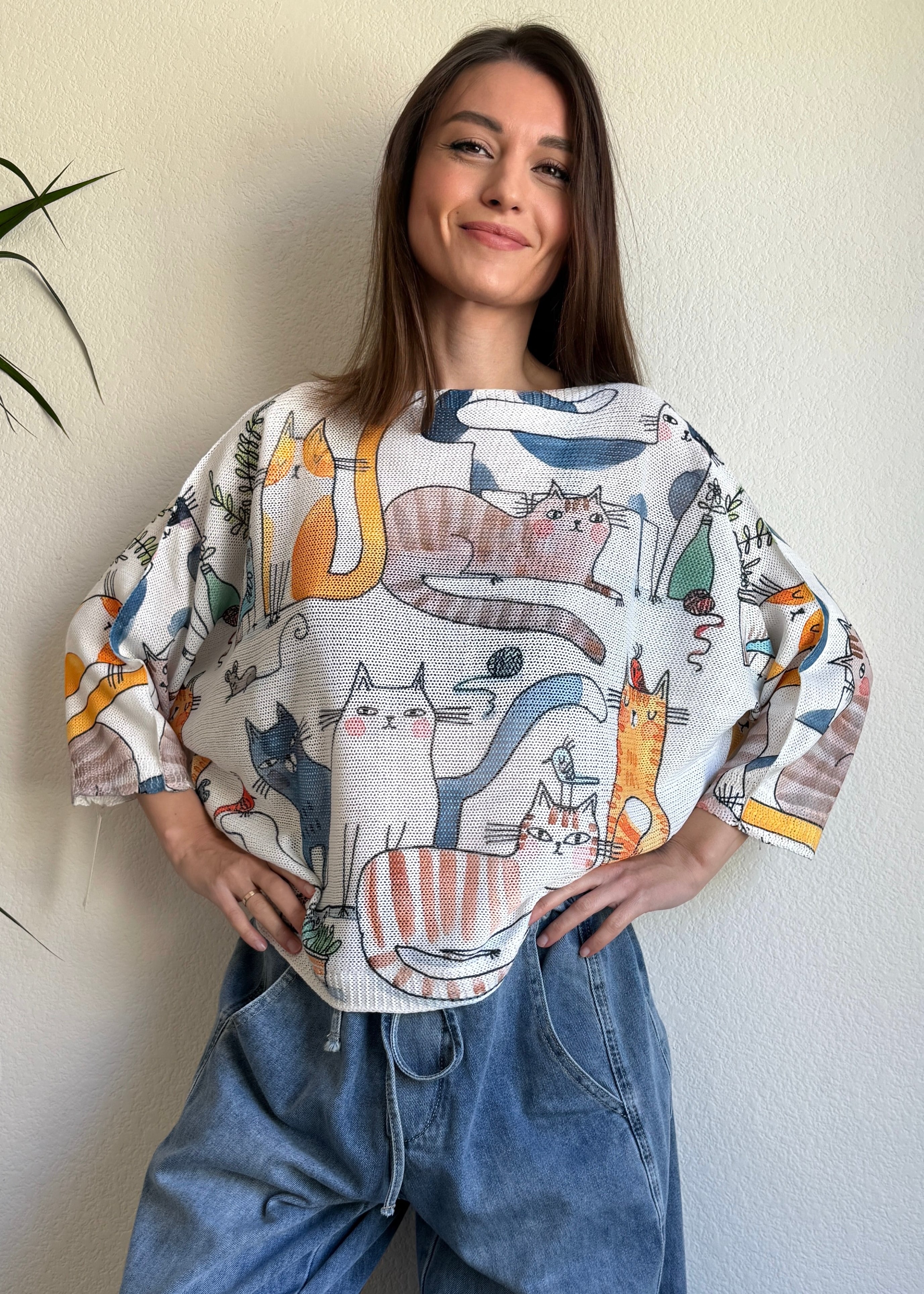 Lifestyle image of model wearing the playful cats print batwing sweater in a casual setting