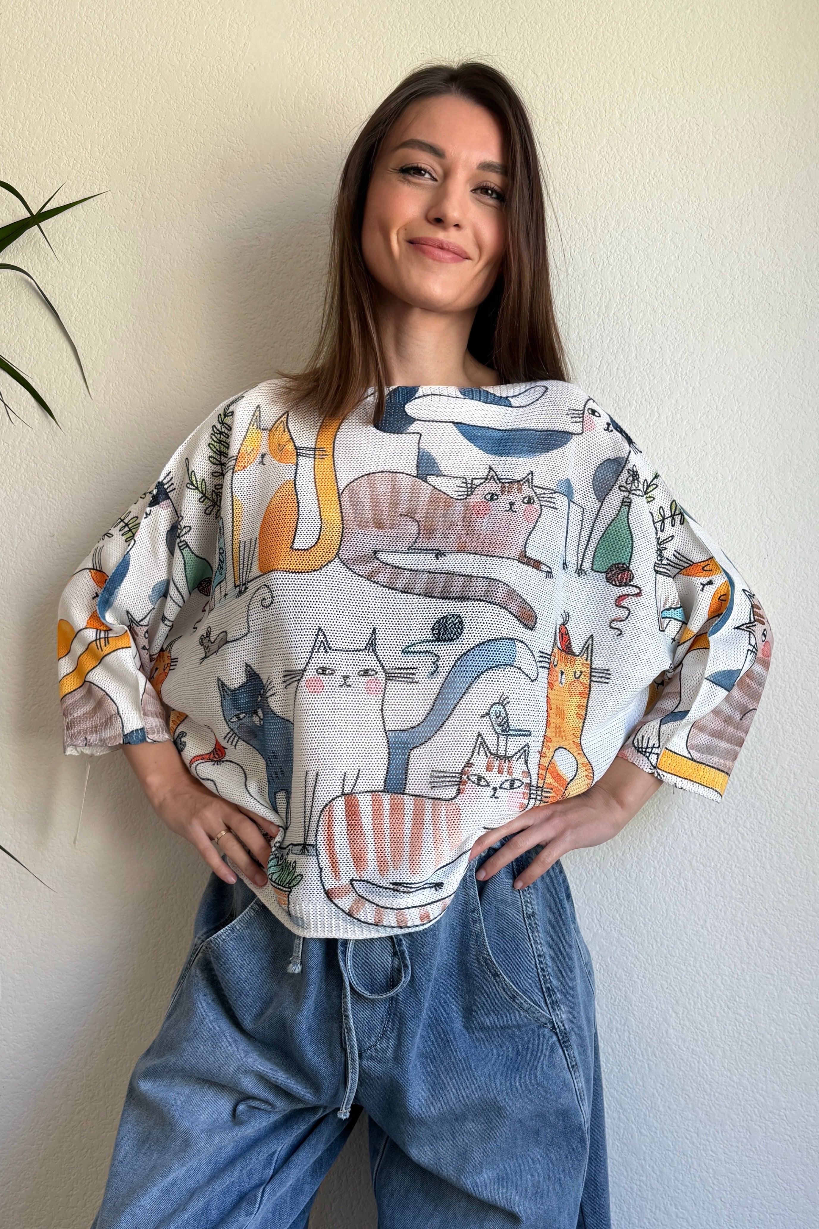 Lifestyle image of model wearing the playful cats print batwing sweater in a casual setting