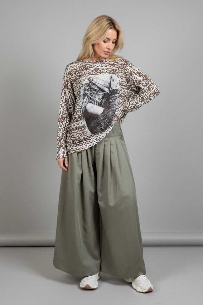 Full-body view of the batwing cowgirl print sweater styled with wide-leg pants