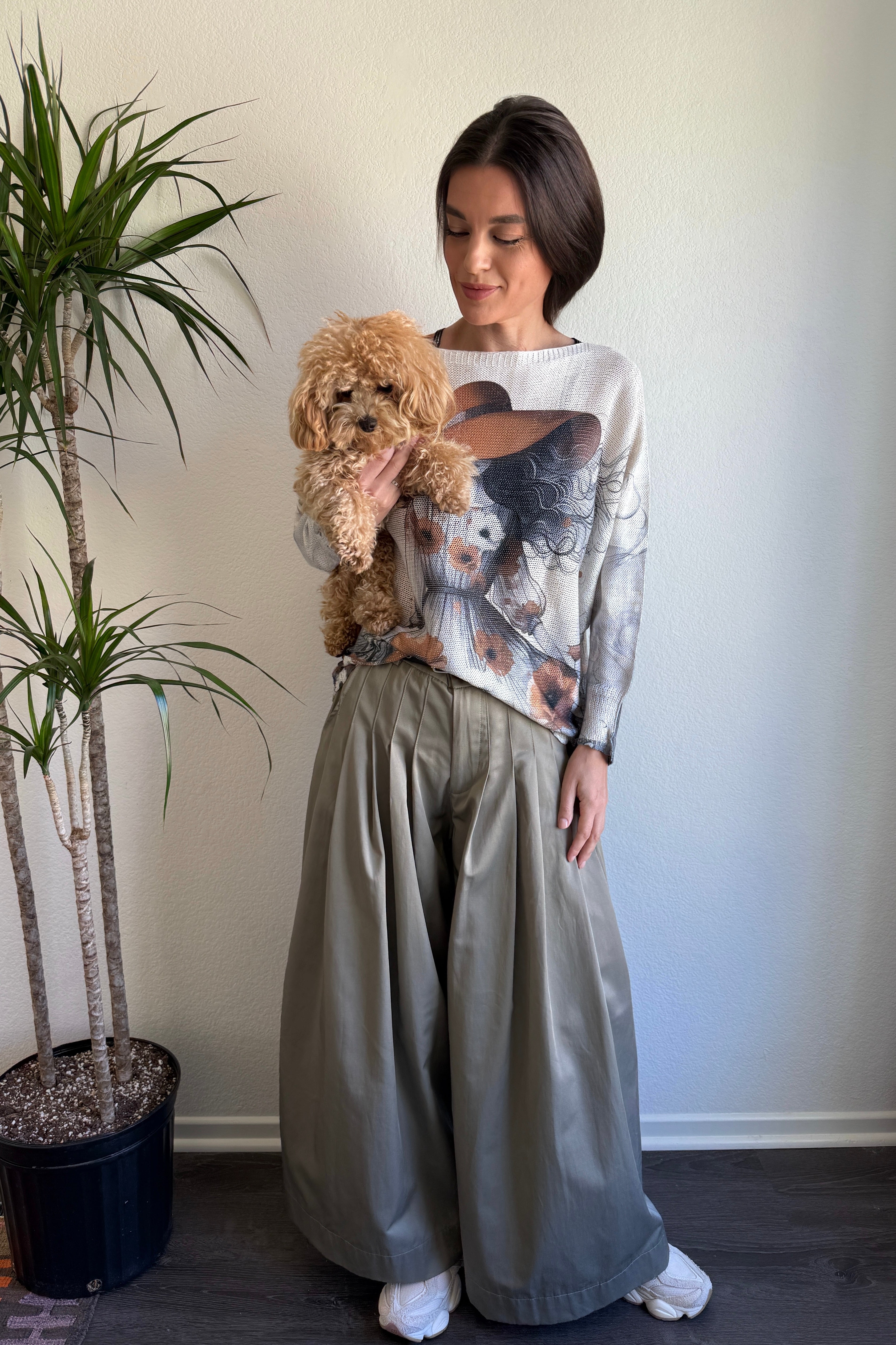 Lifestyle image of model wearing the batwing printed sweater while holding a small dog
