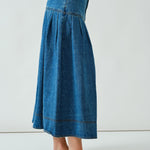 Side walking view of the denim midi skirt showing drape and volume