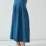 Side walking view of the denim midi skirt showing drape and volume