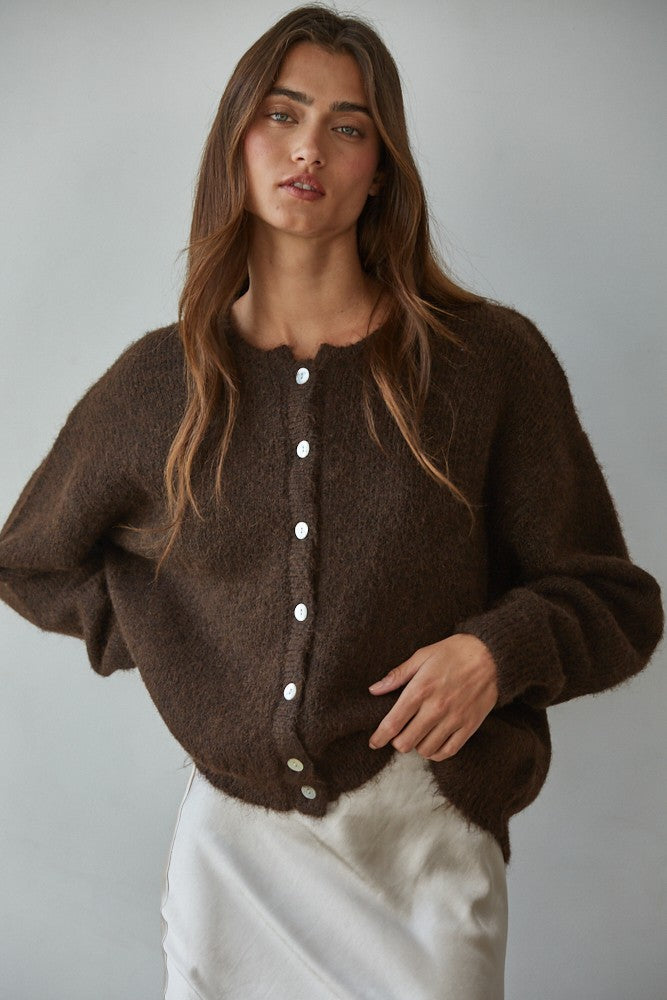 Woman wearing Lucas Button Down  brown cardigan with white buttons against a plain background