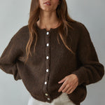 Woman wearing Lucas Button Down  brown cardigan with white buttons against a plain background