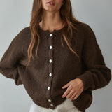 Woman wearing Lucas Button Down  brown cardigan with white buttons against a plain background