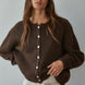 Woman wearing Lucas Button Down  brown cardigan with white buttons against a plain background