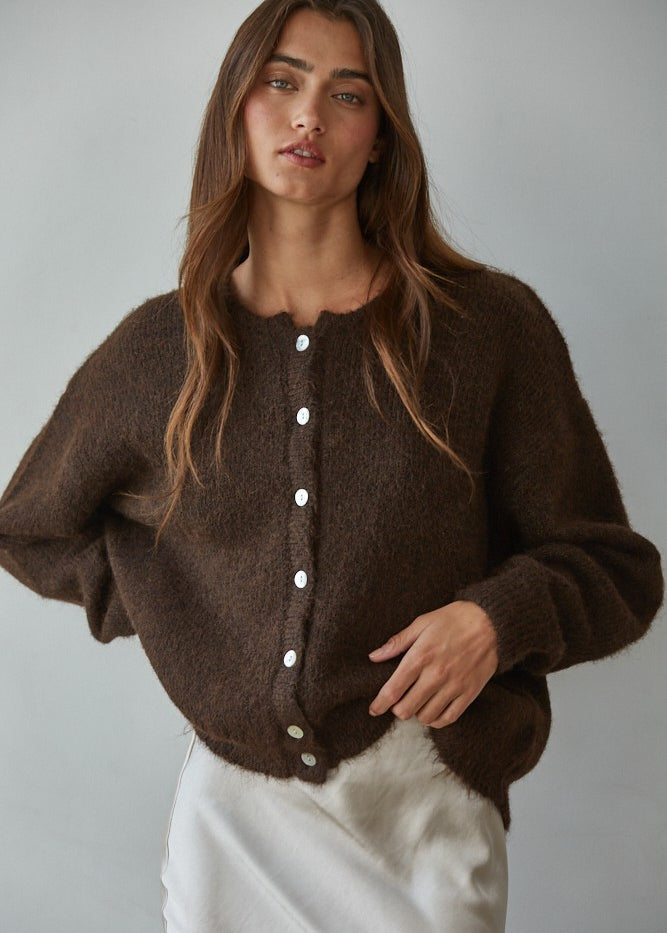 Woman wearing Lucas Button Down  brown cardigan with white buttons against a plain background