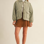 Full-body front view of the Magnolia Wave Quilted Cotton Jacket in olive styled with a skirt