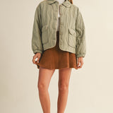 Full-body front view of the Magnolia Wave Quilted Cotton Jacket in olive styled with a skirt