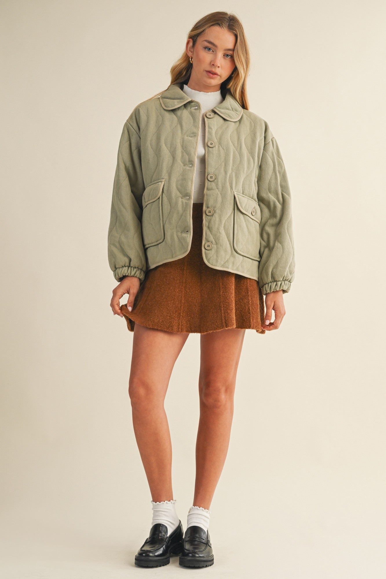 Full-body front view of the Magnolia Wave Quilted Cotton Jacket in olive styled with a skirt