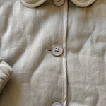 Close-up of a beige corduroy jacket with buttons on a neutral background