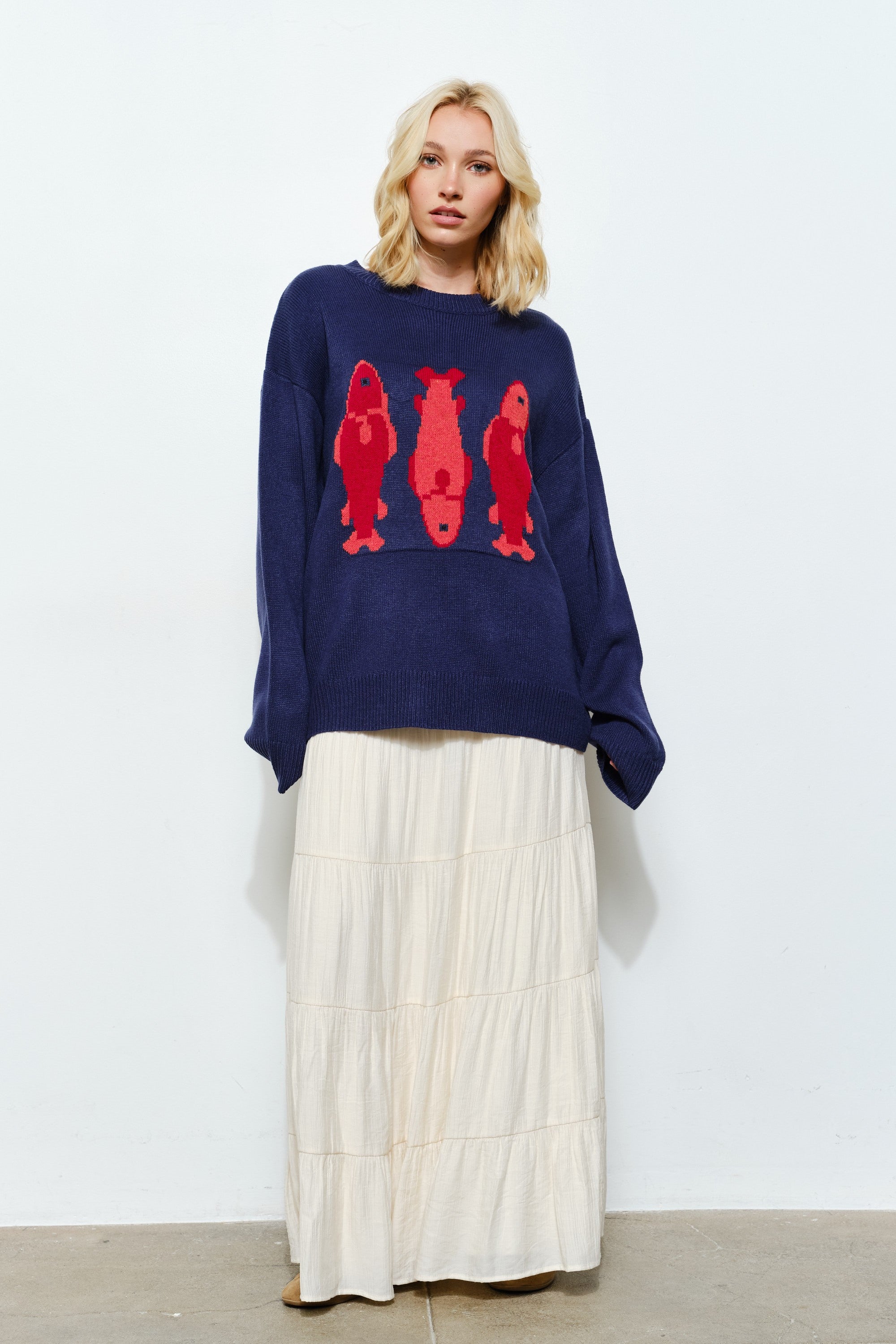Woman wearing the Marina Fish Knit Sweater in navy — chunky oversized knit with bold red fish embroidering.