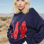 Close-up of the red fish sardine motif on the Marina Fish Knit Sweater — playful pattern on soft navy knit fabric.